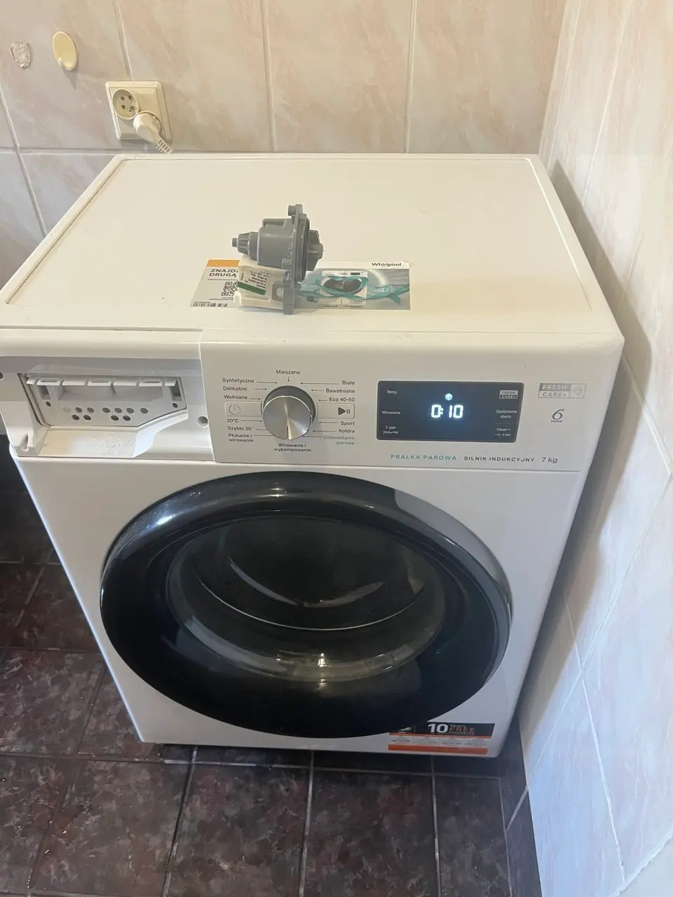 Naprawa pralek Whirlpool – serwisant naprawiający pralkę z użyciem narzędzi diagnostycznych