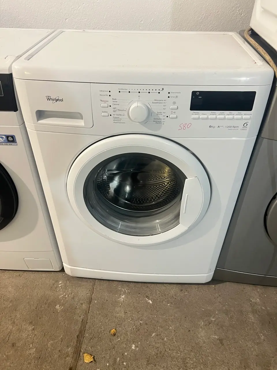 Naprawa pralek Whirlpool – serwisant naprawiający pralkę z użyciem narzędzi diagnostycznych